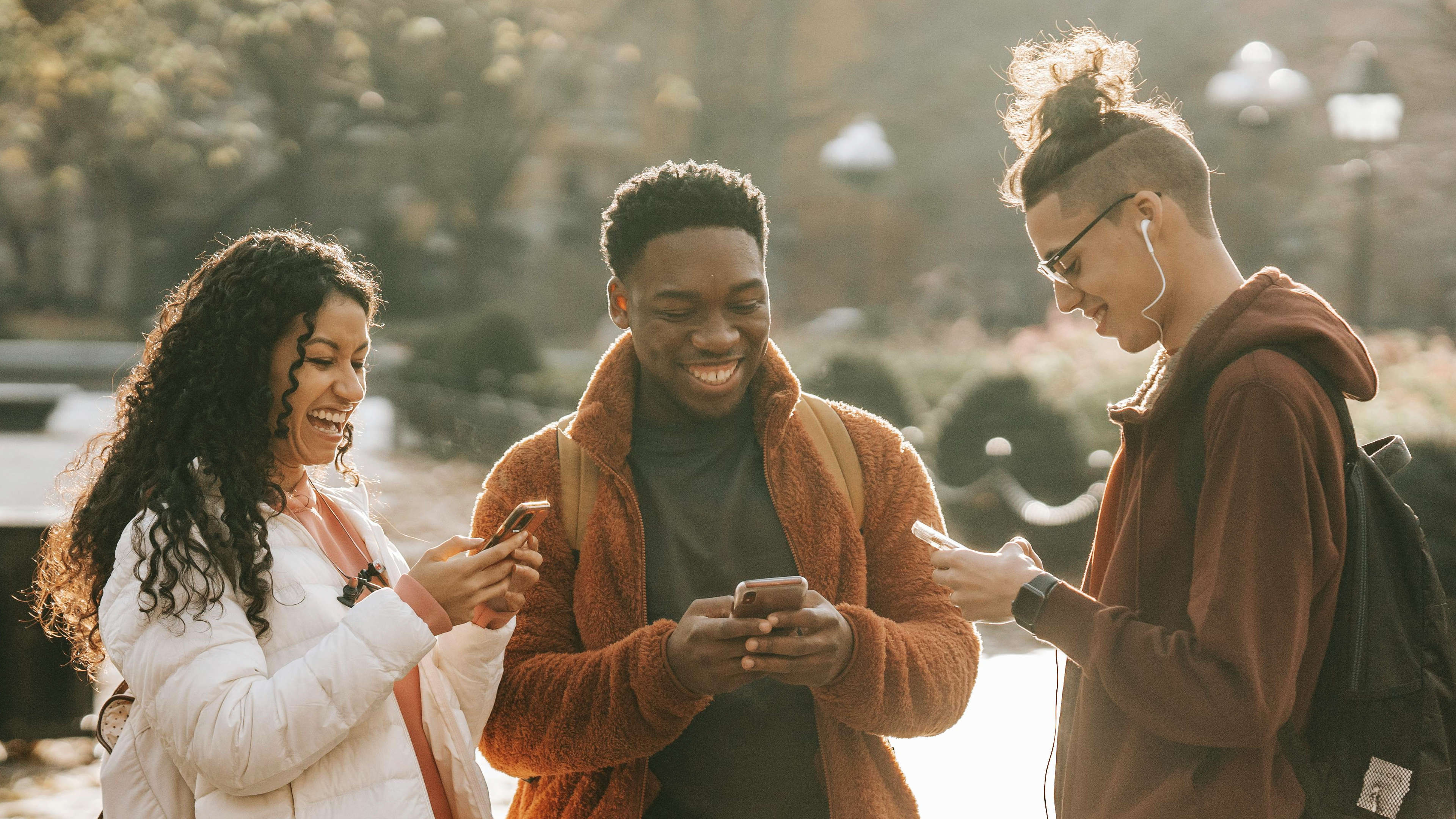 Three Students on Mobile Devices Smiling