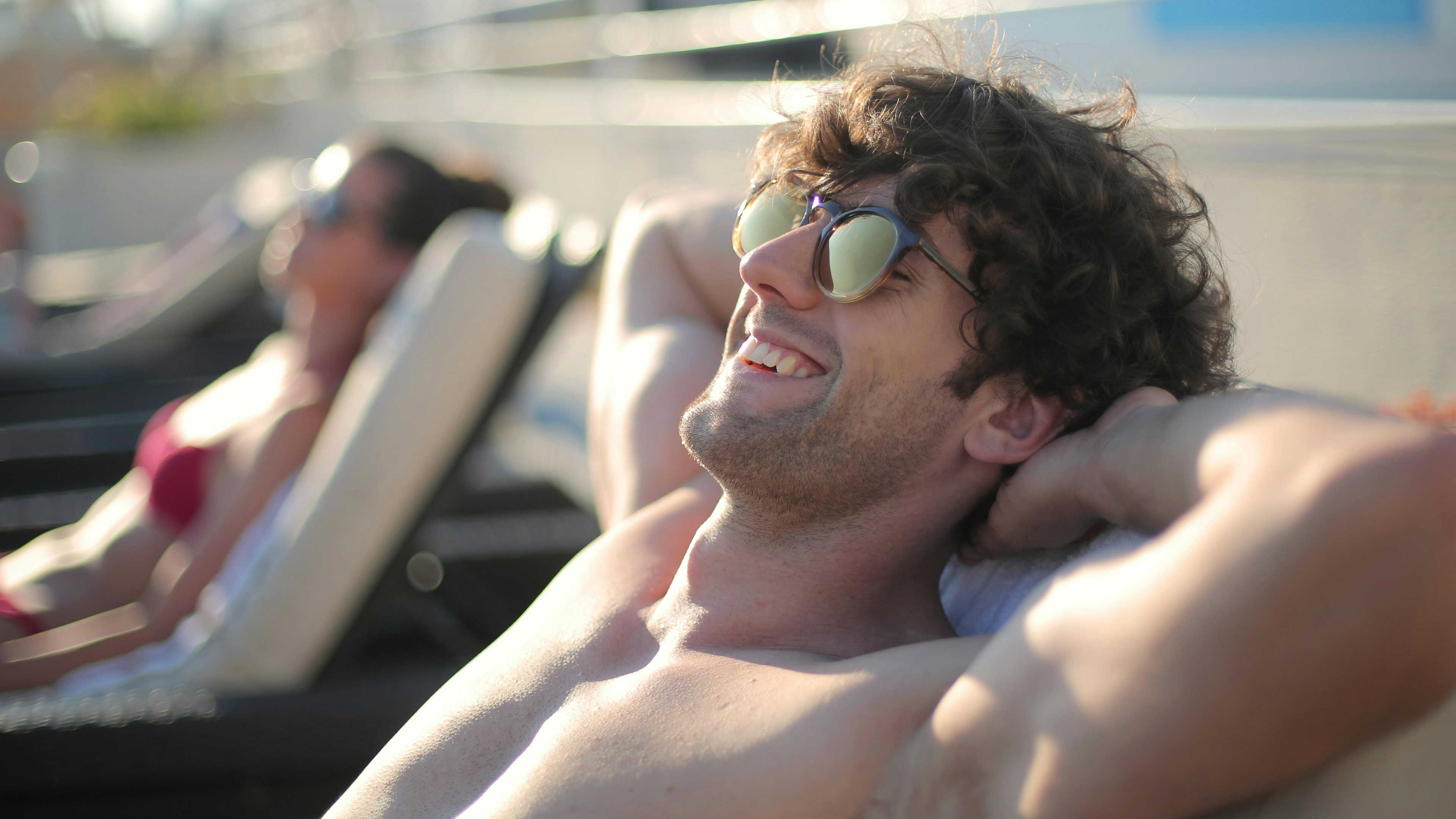 A man laying on a chaise with sunglasses