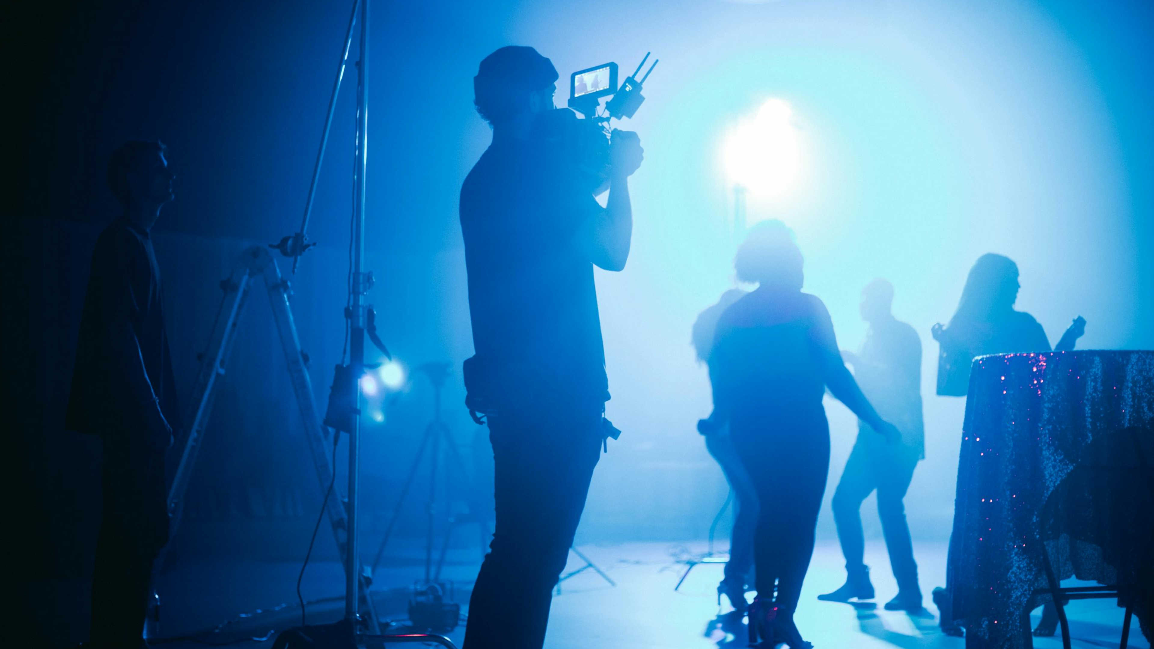 A man filming an event on set with lights and action