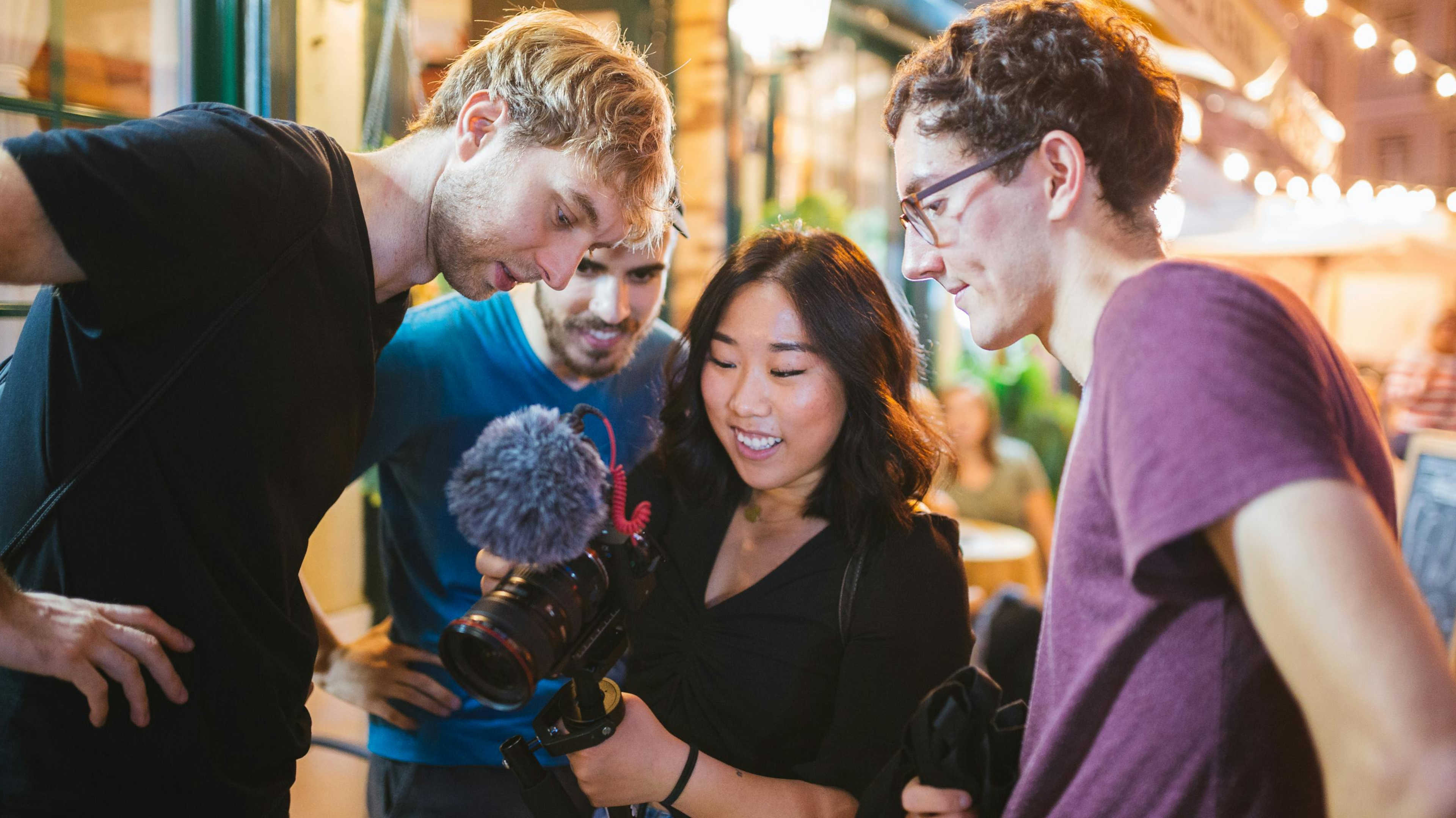 A woman reviewing footage on her camera, surrounded by friends