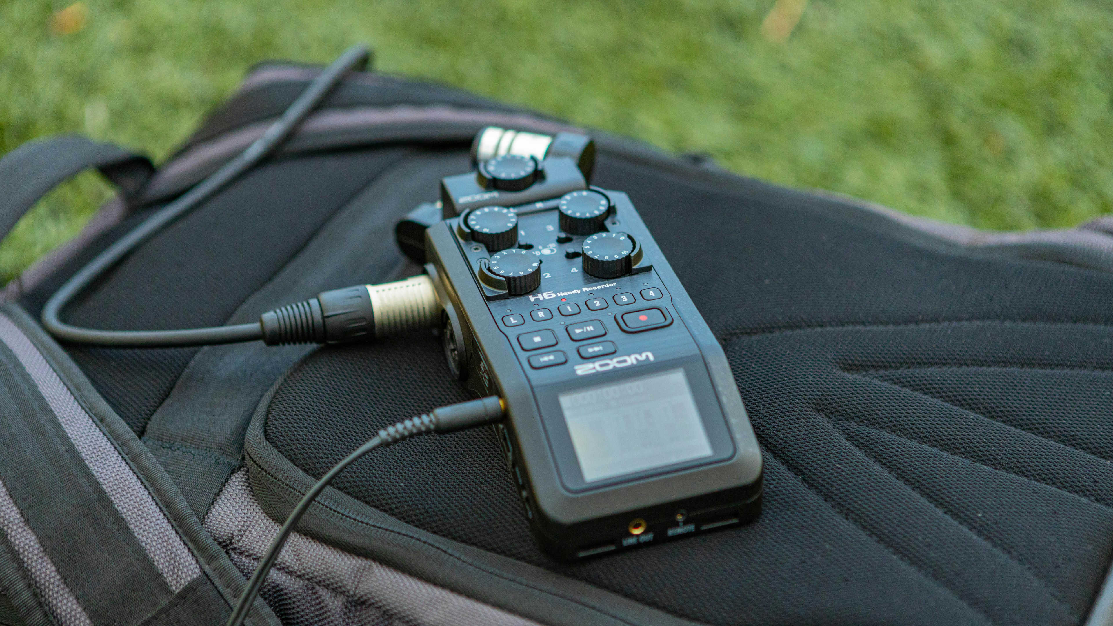 A portable Zoom audio recorder on top of a backpack