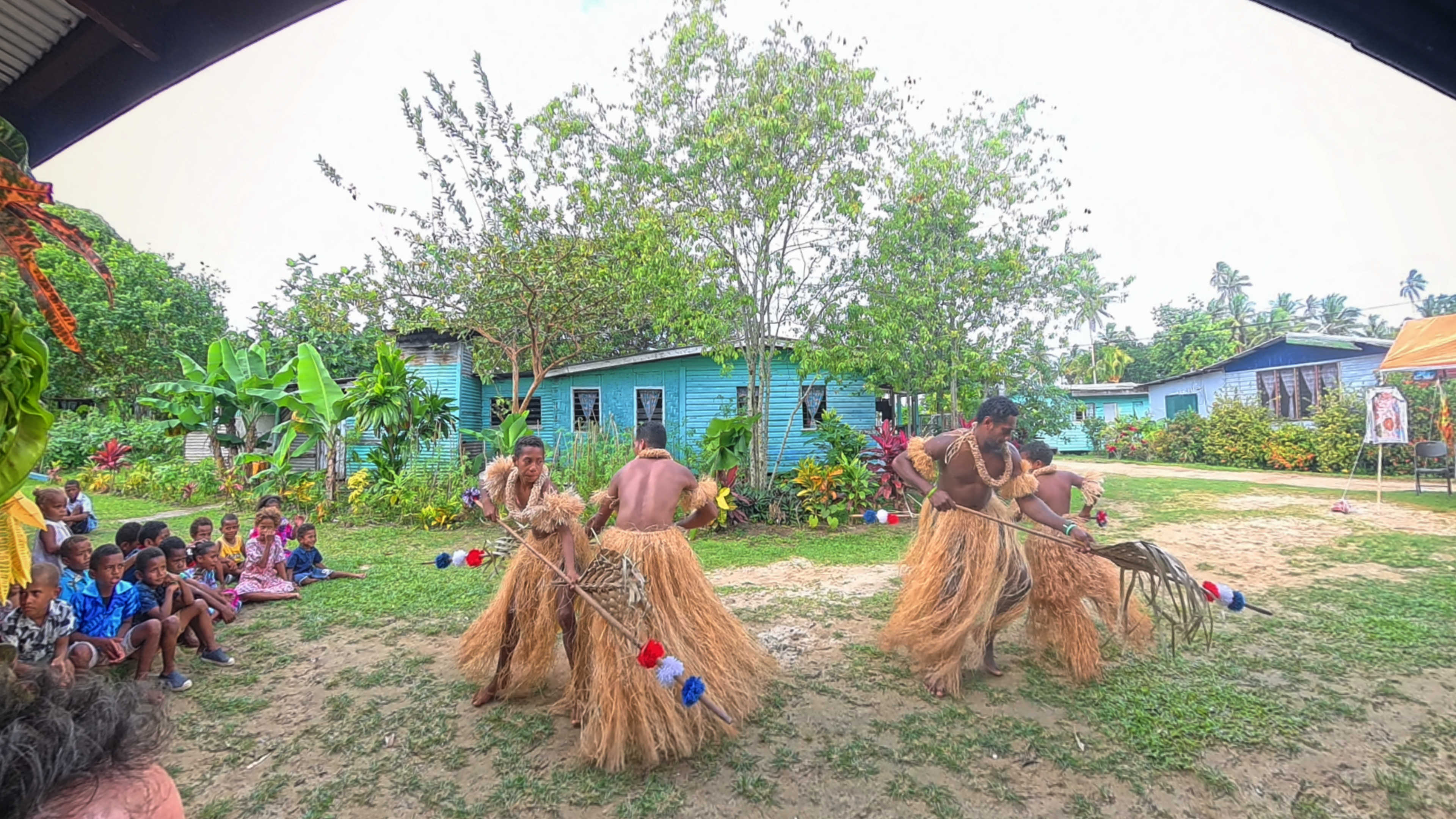 Four men in grass skirts dancing in a performance in Nukubalavu village