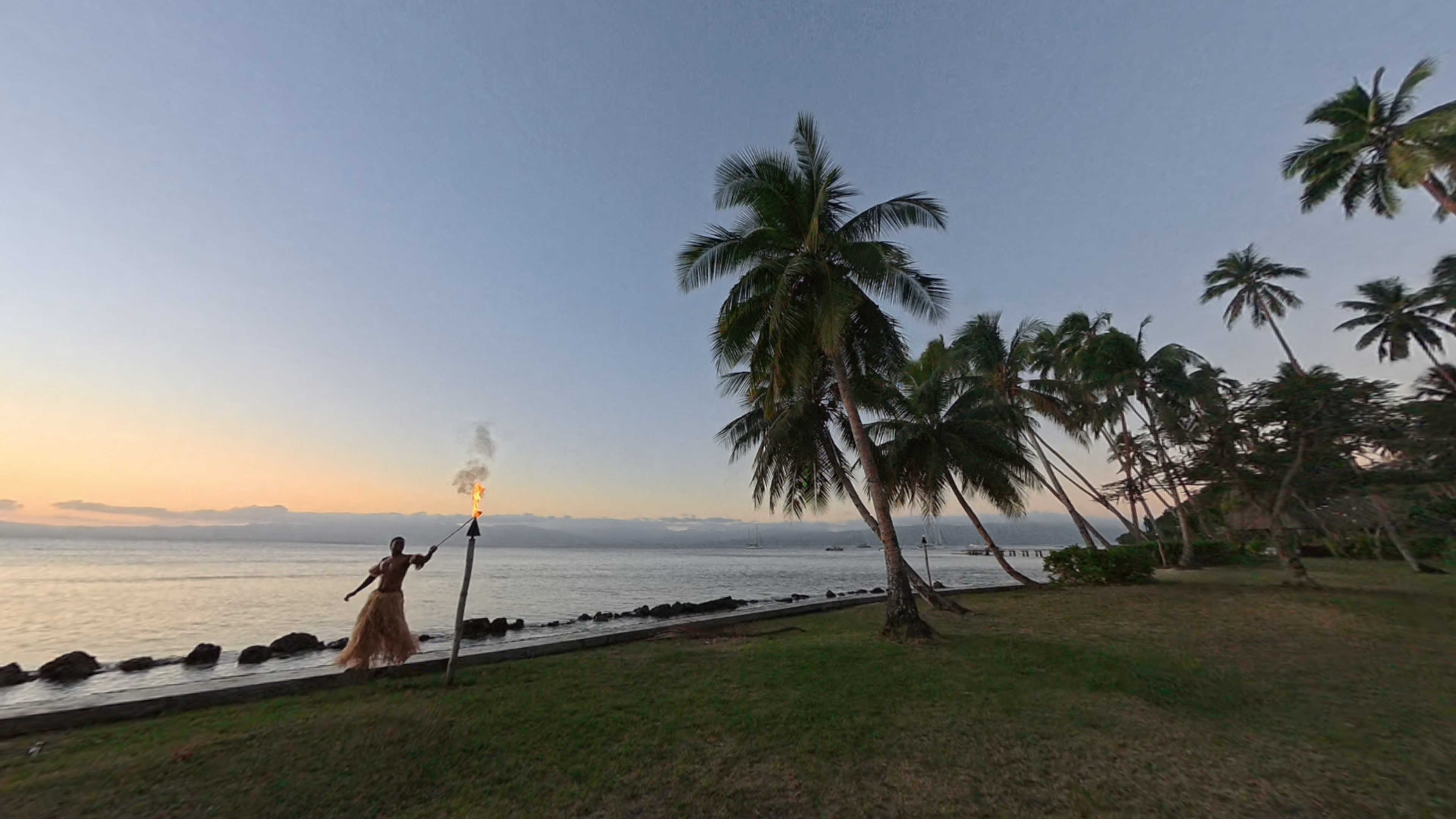 A man in a grass skirt lighting a torch