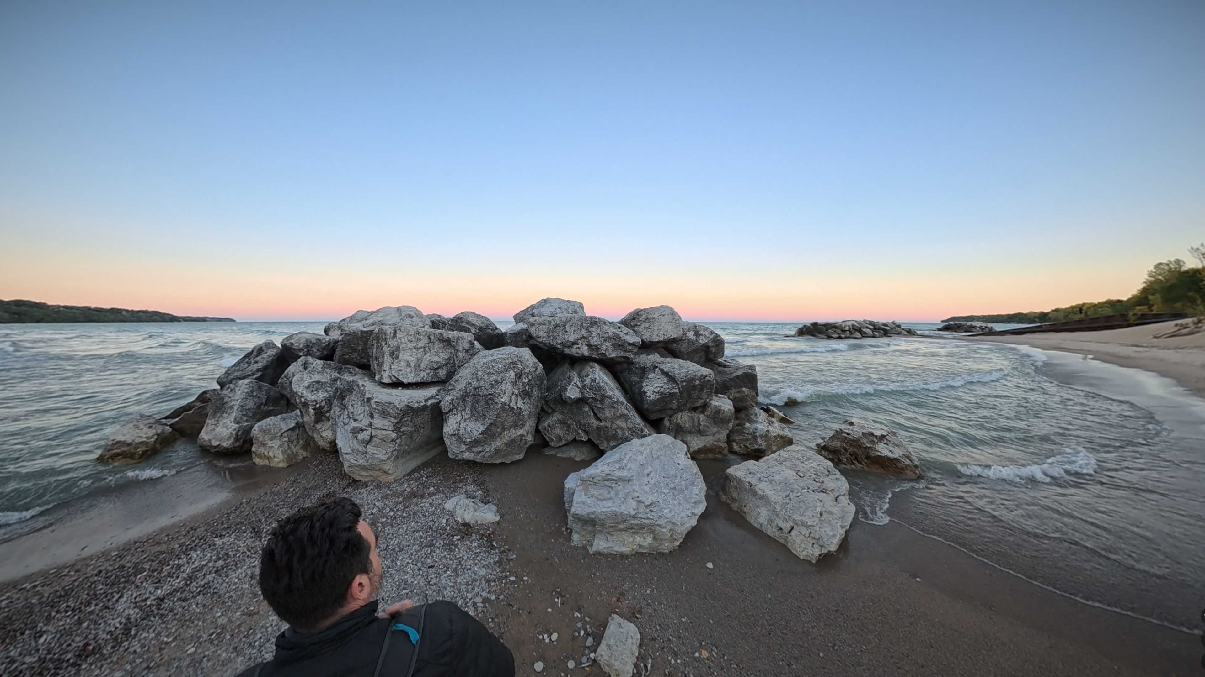 Me walking down the beach, towards a pile of large rocks at the water's edge